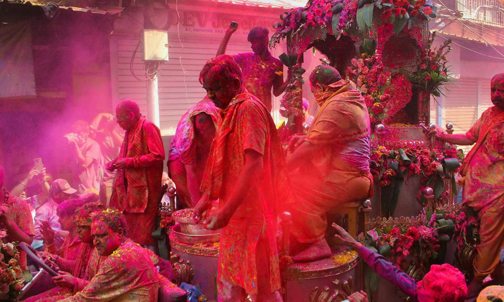 Devotees celebrating Holi in Vrindavan temple with vibrant gulal colors